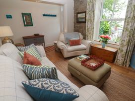 A living room with a sofa, chair, and coffee table at Kittiwake in Penzance