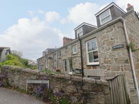 A row of houses with a stone wall and signage at Kittiwake in Newlyn