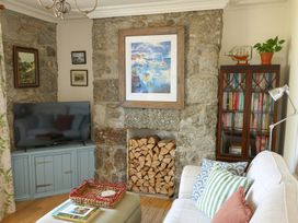 A living room with a television and a stone wall at Kittiwake Newlyn