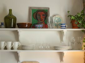 A kitchen shelf with dishes and glasses at Kittiwake in Newlyn