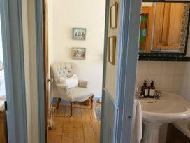 A bathroom with a sink and an armchair at Kittiwake Newlyn