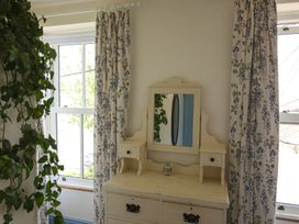 A dresser with a mirror and curtains in a bedroom at Kittiwake in Newlyn