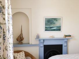 A bedroom with a painting, decorative items, and a sailing boat at Kittiwake in Newlyn
