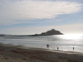 A beach scene with people walking by the water at Kittiwake in Newlyn