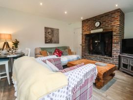 A living room with sofas, a wooden coffee table, a brick fireplace, and a dining table with chairs at Ellesmere Cottage in Hornsea
