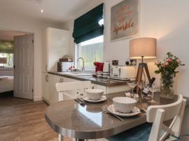 A kitchen with a breakfast bar set for two with bowls and plates and a countertop with appliances and a lamp at Ellesmere Cottage in Hornsea