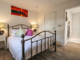 A bedroom with a metal bed frame two bedside tables lamps and an open door to a bathroom at Ellesmere Cottage in Hornsea