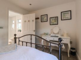 A bedroom with a metal bed frame white dressing table with mirror and three framed pictures on the wall at Ellesmere Cottage in Hornsea