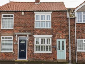 A brick terraced house with two entrance doors and white framed windows in Aldbrough