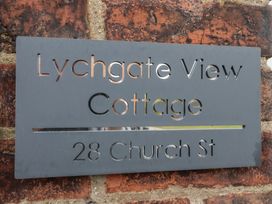 A metal sign mounted on a brick wall with text Lychgate View Cottage 28 Church St at Lychgate View Cottage in Aldbrough