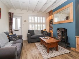 A living room with two sofas a wooden coffee table and a fireplace at Lychgate View Cottage in Aldbrough