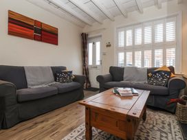 A living room with two sofas a wooden coffee table and a window with shutters at Lychgate View Cottage in Aldbrough