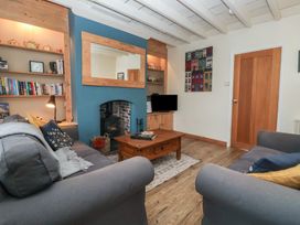 A living room with two grey sofas a wooden coffee table a wood burning stove and bookshelves at Lychgate View Cottage in Aldbrough