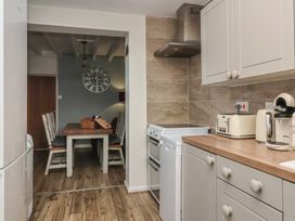 A kitchen with countertop appliances and a dining area with wooden table and chairs at Lychgate View Cottage in Aldbrough