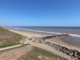 A sandy beach with rock barriers extending into the sea and a walking path near the shore at Lychgate View Cottage in Aldbrough
