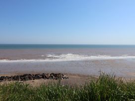 A beach view with waves and rocks seen from behind grass at Lychgate View Cottage in Aldbrough
