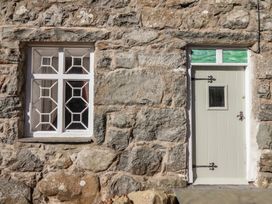 A stone wall with a window and a door with green glass panels at Clywedog Cottage in Dolgellau