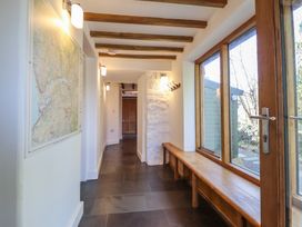 A hallway with a wooden bench and coat hooks next to large windows and a map on the wall at Clywedog Cottage in Dolgellau
