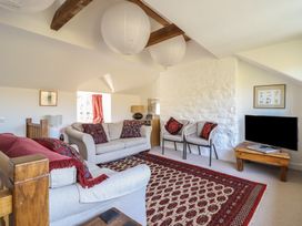 A living room with sofas chairs a patterned rug and a television at Clywedog Cottage in Dolgellau