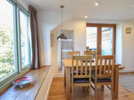 A dining area with a wooden table and chairs near a window and glass door at Clywedog Cottage in Dolgellau