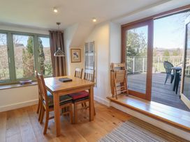 A dining area with wooden table and chairs next to large windows and sliding glass door opening to a deck at Clywedog Cottage in Dolgellau