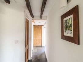A hallway with wooden doors stone floor beams on the ceiling and a framed picture on the wall at Clywedog Cottage in Dolgellau