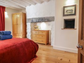 A bedroom with a red bedspread blue towels wooden wardrobe and chest of drawers at Clywedog Cottage in Dolgellau