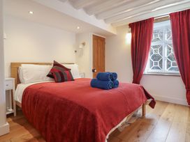 A bedroom with a double bed covered in a red blanket and blue towels placed on top at Clywedog Cottage in Dolgellau