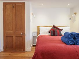 A bedroom with a wooden door a bed with red bedding striped pillows and blue rolled towels at Clywedog Cottage in Dolgellau