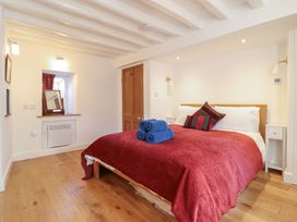 A bedroom with a double bed covered in a red blanket and blue towels on top at Clywedog Cottage in Dolgellau