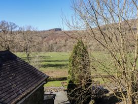 A view of a green field with grazing sheep trees and a roofed stone building at Clywedog Cottage in Dolgellau