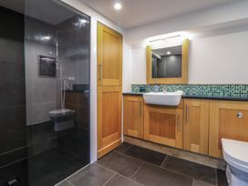 A bathroom with a walk-in shower toilet sink wooden cabinets and a mirror at Clywedog Cottage in Dolgellau