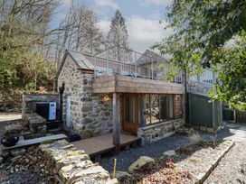 An exterior view of a stone cottage with a wooden balcony and gravel pathway at Clywedog Cottage in Dolgellau