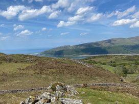 A landscape with hills rocks stone walls and a body of water under a partly cloudy sky at Clywedog Cottage in Dolgellau