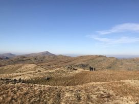 A mountainous landscape with dry grass and three people walking at Clywedog Cottage in Dolgellau