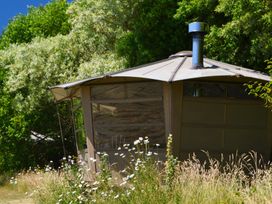 A small round cabin with a chimney surrounded by wildflowers and tall grass at Caban Llwynon in Tresillian Wood near Llantwit Major