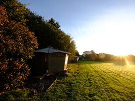 A grassy field with small cabins near trees at Caban Llwynon in Tresillian Wood near Llantwit Major