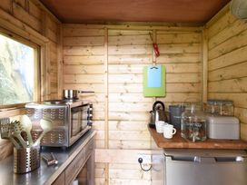 A small kitchen area with a toaster oven pot utensils kettle cups and a water dispenser at Caban Llwynon in Tresillian Wood near Llantwit Major