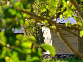 Small cabins with pitched metal roofs behind leafy branches in a wooded area at Caban Llwynon in Tresillian Wood near Llantwit Major