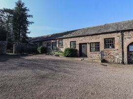 A stone building with several windows and a door with a gravel courtyard at Periwinkle in Akeld near Wooler