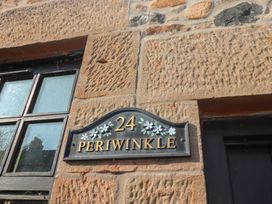 A house number plaque with number 24 and name Periwinkle on a stone wall near a window and door at Periwinkle in Akeld near Wooler