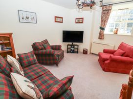 A living room with plaid sofas a television and a window at Periwinkle in Akeld near Wooler
