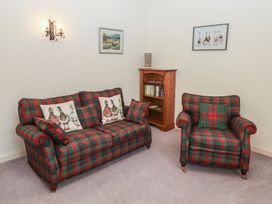 A living room with a plaid sofa and armchair cushions and framed pictures on the wall at Periwinkle in Akeld near Wooler