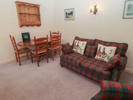 A small dining area with wooden table and chairs next to a plaid sofa with duck printed cushions at Periwinkle in Akeld near Wooler