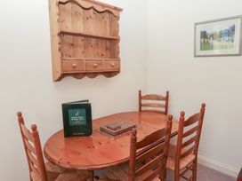 A dining area with a wooden table and four chairs a wall-mounted wooden shelf and a framed picture at Periwinkle in Akeld near Wooler