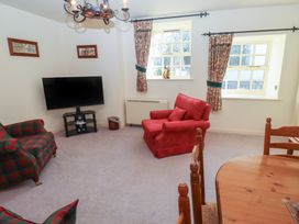 A living room with armchairs television and wooden dining table at Periwinkle in Akeld near Wooler