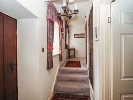 A hallway with carpeted steps curtains on windows and wooden doors at Periwinkle in Akeld near Wooler