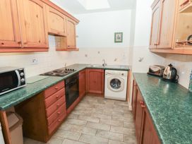 A kitchen with wooden cabinets green countertops a microwave washing machine toaster and kettle at Periwinkle in Akeld near Wooler