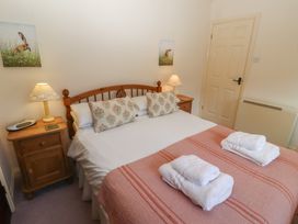A bedroom with a double bed bedside tables lamps and folded towels at Periwinkle in Akeld near Wooler