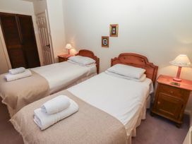 A bedroom with two single beds each with a bedside table and lamp at Periwinkle Akeld near Wooler